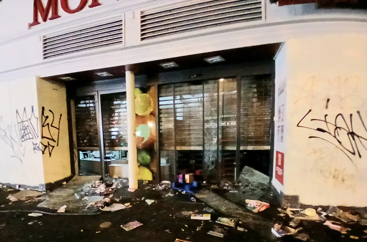 Vitrine et fermeture métallique endommagées d’un commerce à Paris, avec du verre et des débris au sol, le 18 octobre 2026.