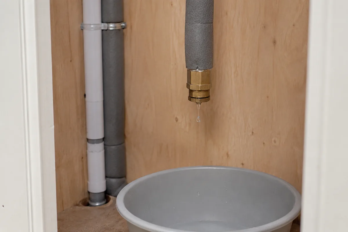 Goutte sous un bouchon de canalisation dans un placard domestique.